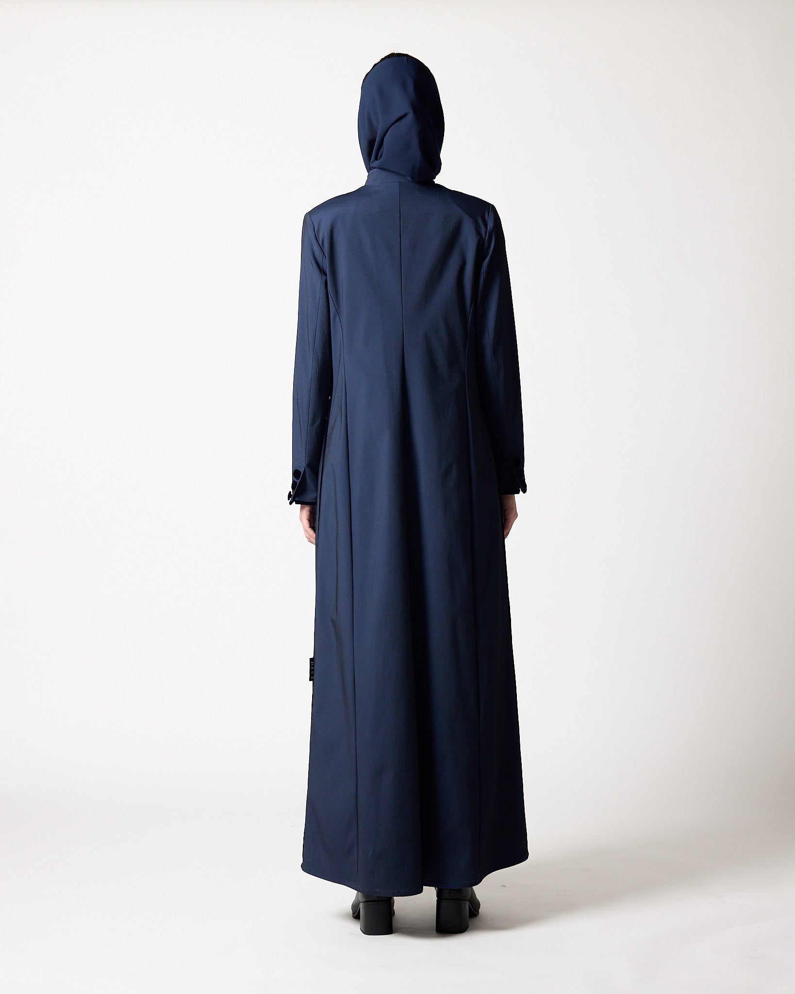 A person viewed from the back wearing a long navy hooded coat or abaya against a plain light studio عبايات قطر | Abaya Qatar
عبايات الدوحة | Abayas Doha
عباية قطر | Abaya Doha
عبايات اونلاين قطر | Abayas Online Qatar
عبايات أونلاين قطر | Online Abayas Qatar
شراء عبايات قطر | Buy Abaya Qatar
شراء عبايات اونلاين | Buy Abayas Online
متجر عبايات قطر | Abaya Store Qatar
محل عبايات قطر | Abaya Shop Qatar
بوتيك عبايات قطر | Abaya Boutique Qatar
عبايات نسائية قطر | Ladies Abayas Qatar
عبايات فخمة قطر | Lbackground.